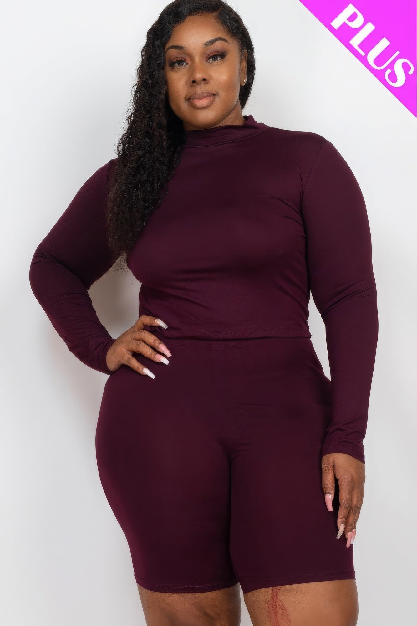 Plus-size woman wearing a stylish burgundy mock neck top and biker shorts set for a fashionable and comfortable look.