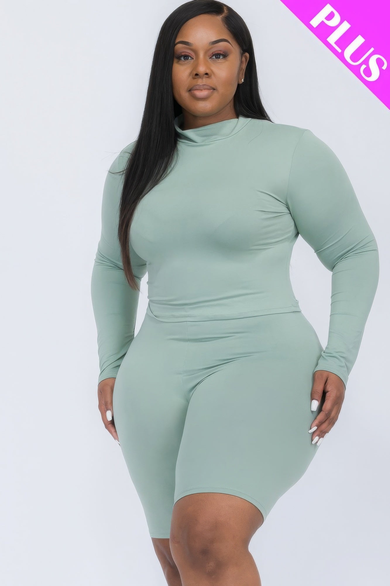 Plus-size woman wearing green mock neck top and biker shorts set, highlighting stylish and comfortable plus-size fashion ensemble.