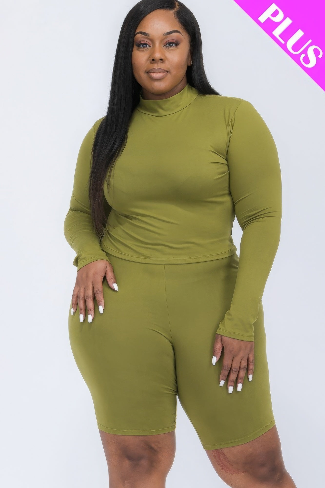 Plus-size woman in green mock neck top and biker shorts set, showcasing comfortable and stylish plus-size fashion ensemble.