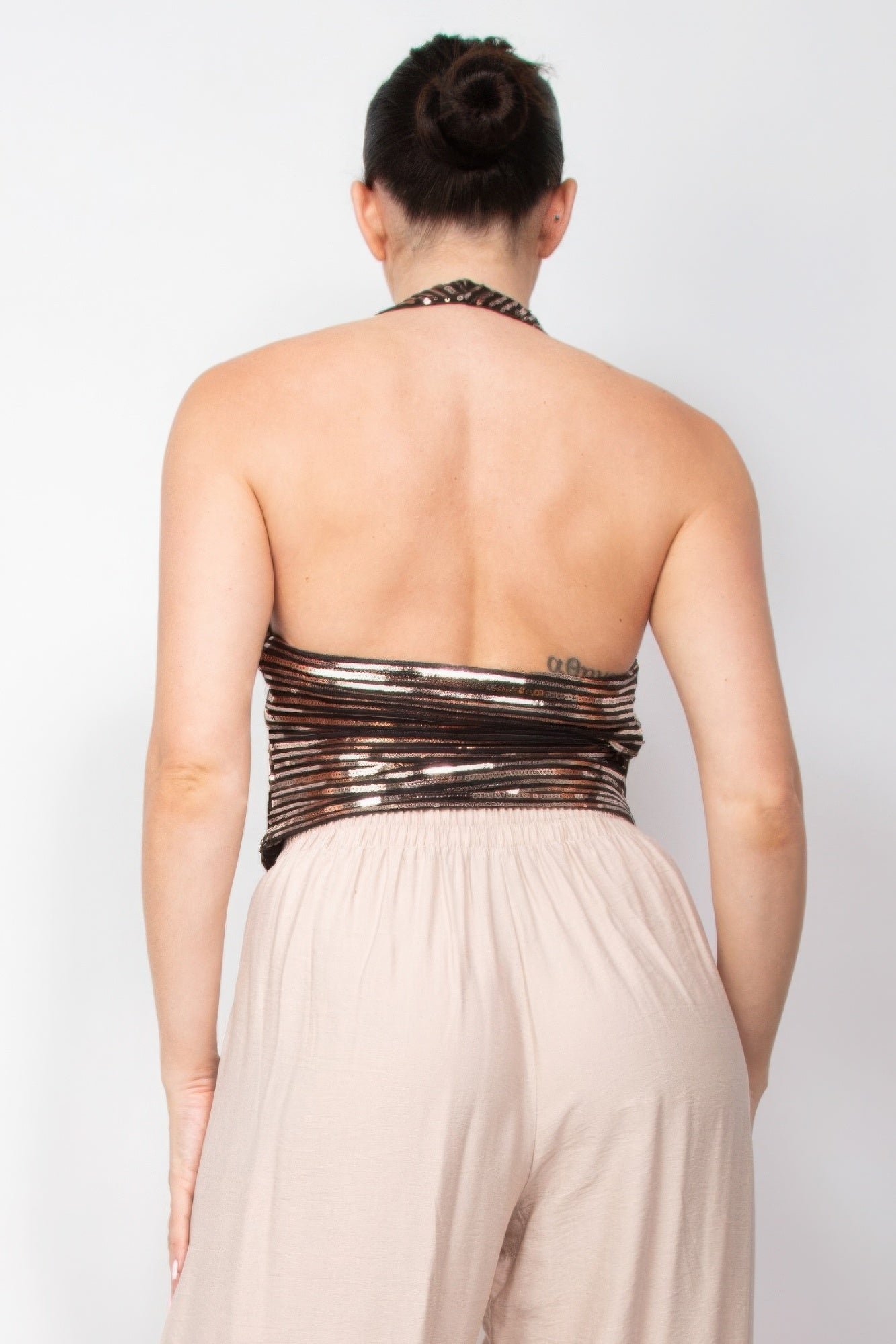 Woman wearing Surplice Halter Sequin Top from Love It Clothing, showcasing back view elegance with shimmering sequin detail.