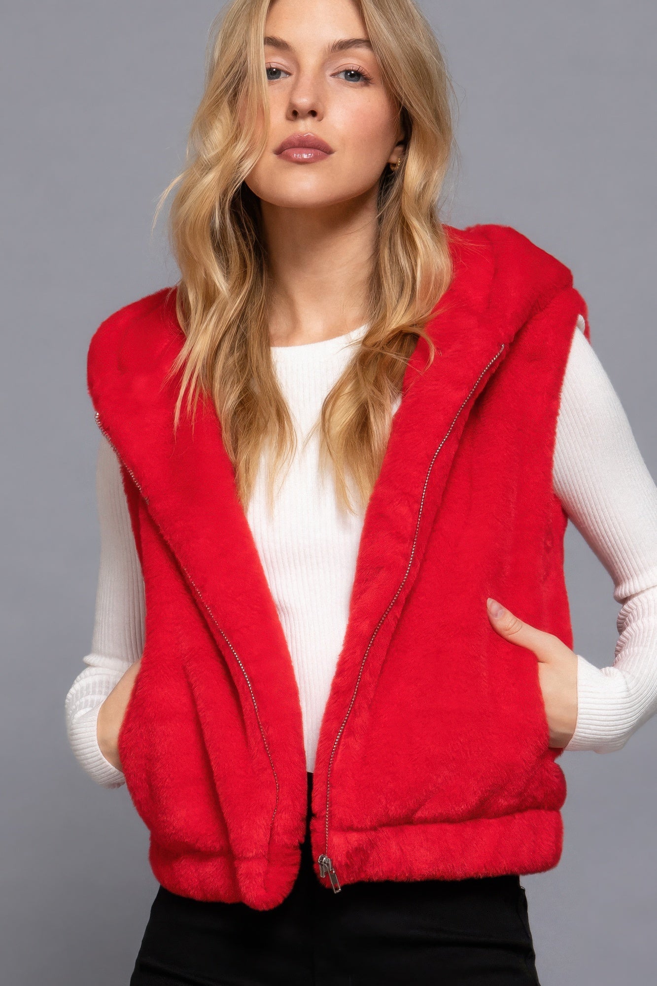 Woman wearing a red faux fur hoodie vest over a white top, showcasing versatile fashion by Love It Clothing.