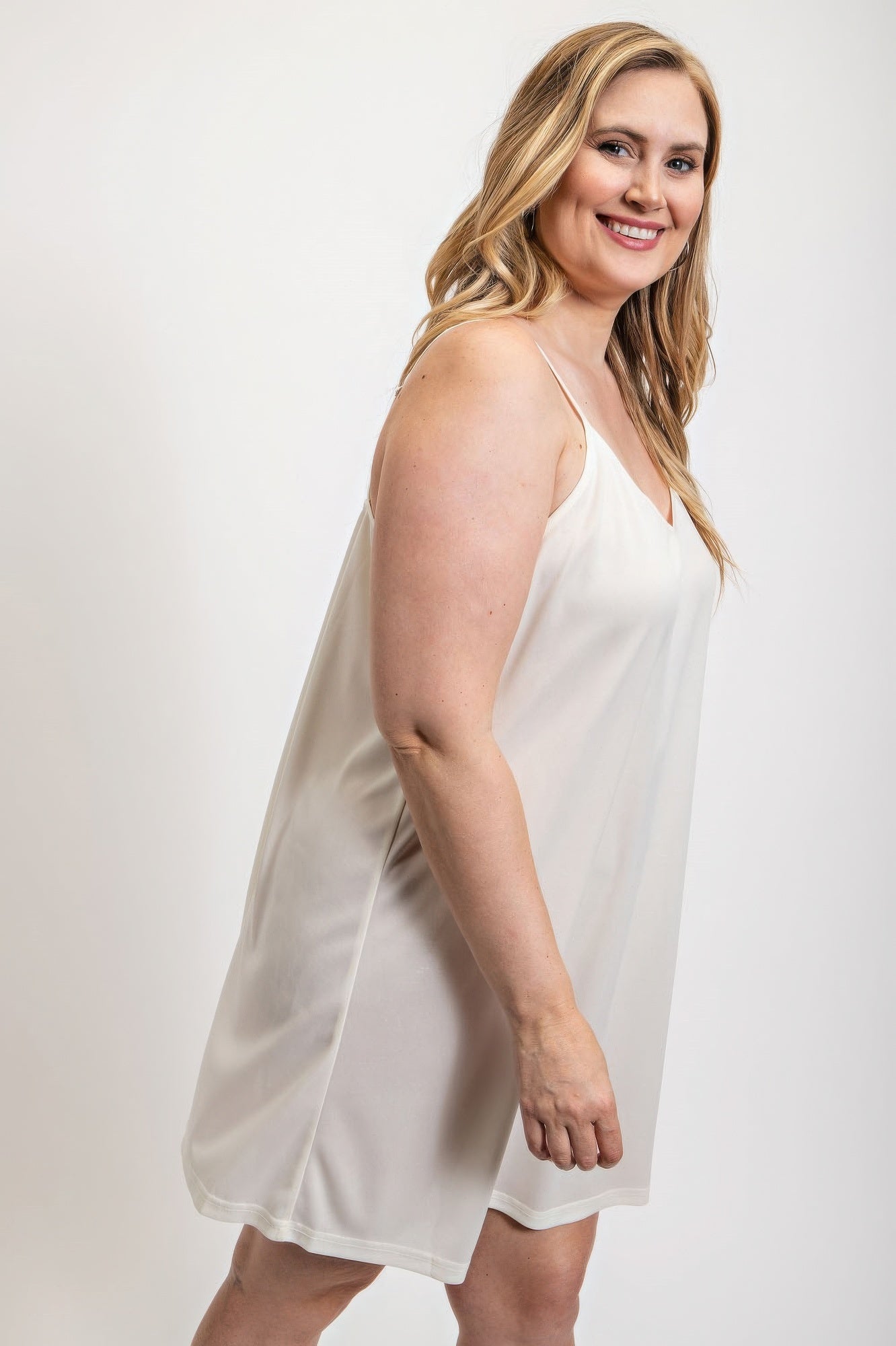 Woman wearing a white V-neck slip dress with adjustable straps from Loveitclothing.com, showcasing elegant and comfortable style.