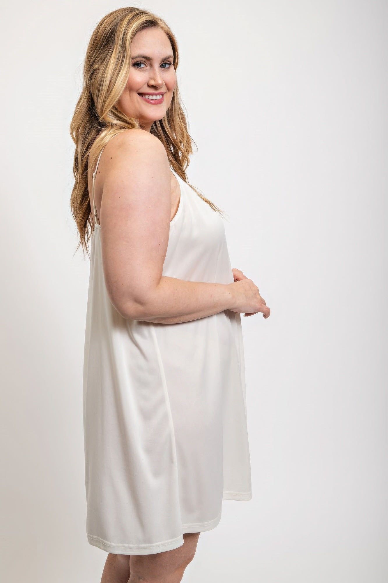 Woman wearing a white V-neck slip dress with adjustable straps from Loveitclothing.com