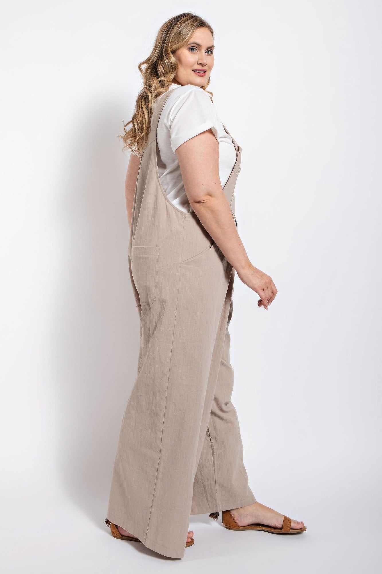 Woman wearing a stone-colored pintuck detail overall with side pockets by Loveitclothing.com.