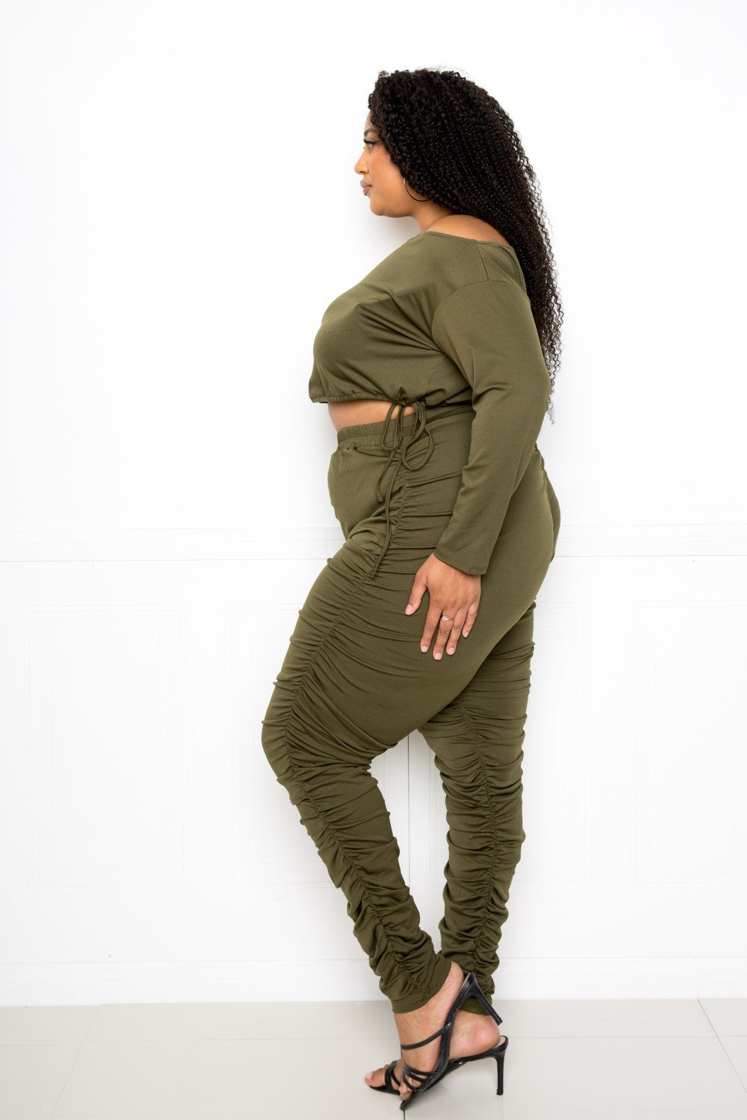 Plus-size model wearing olive Off-Shoulder Cropped Top and Ruched Leggings Set, highlighting stylish fit for curvy figures.