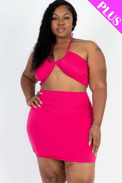 Plus size woman modeling pink crisscross halter top and ruched mini skirt set with plus size label