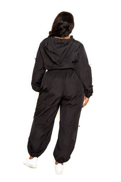 Plus-size model wearing black active zip-up set with cord lock detail from back view, highlighting comfortable fit and style.