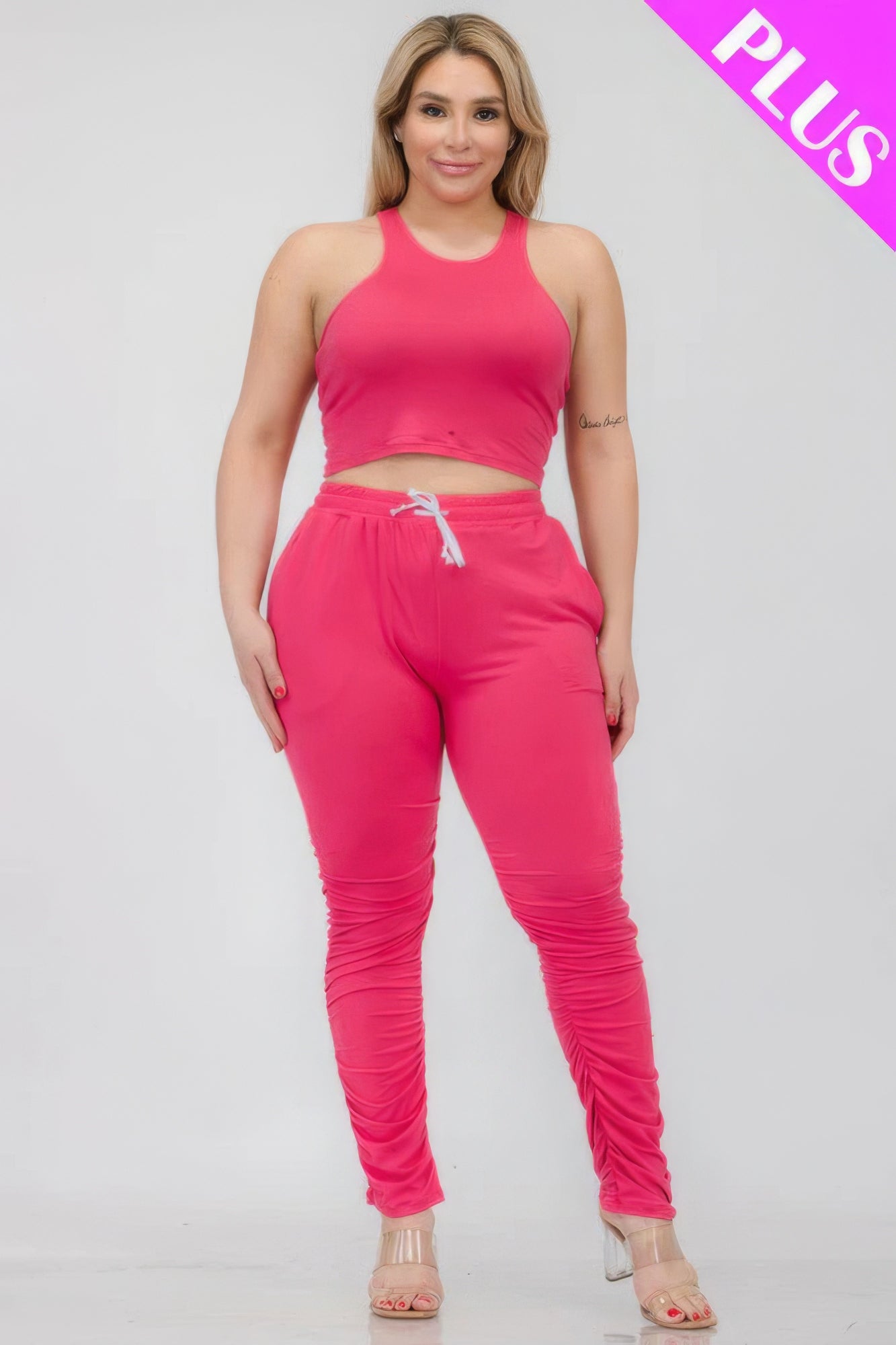 Plus size pink crop tank top and ruched pants set made of polyester and spandex blend for comfort and style.