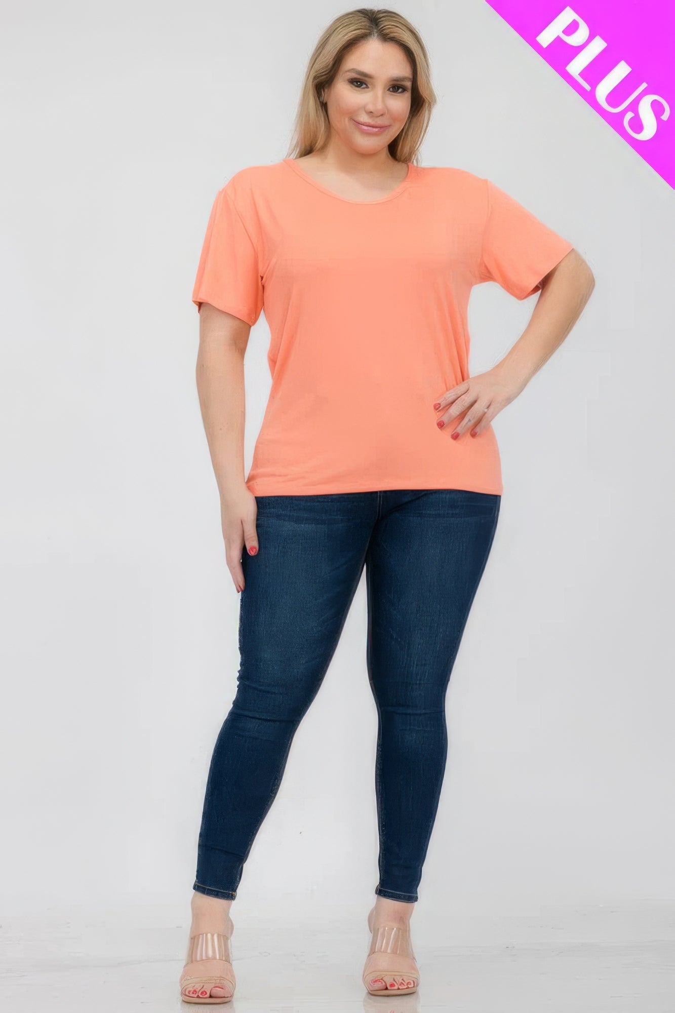 Plus size model wearing a soft, stretchy short sleeve T-shirt in coral, paired with skinny jeans from Loveitclothing.com.