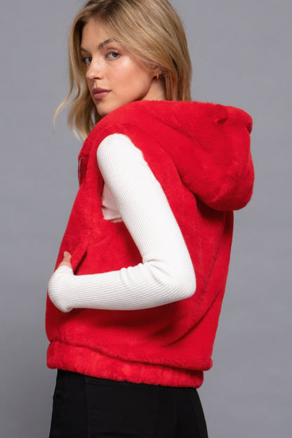 Woman modeling red faux fur vest with hoodie from Love It Clothing, ideal for layering and adding warmth to any outfit.