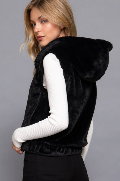 Woman wearing a black faux fur hoodie vest, stylish layering piece from Love It Clothing, ideal for warmth and fashion.