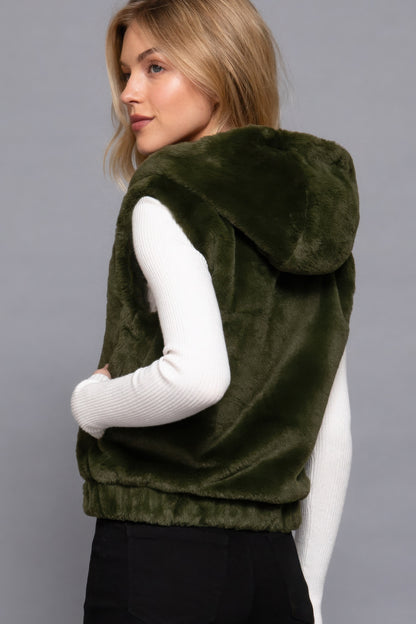 Woman wearing a green faux fur hoodie vest with a relaxed fit, ideal for stylish layering. Love It Clothing.