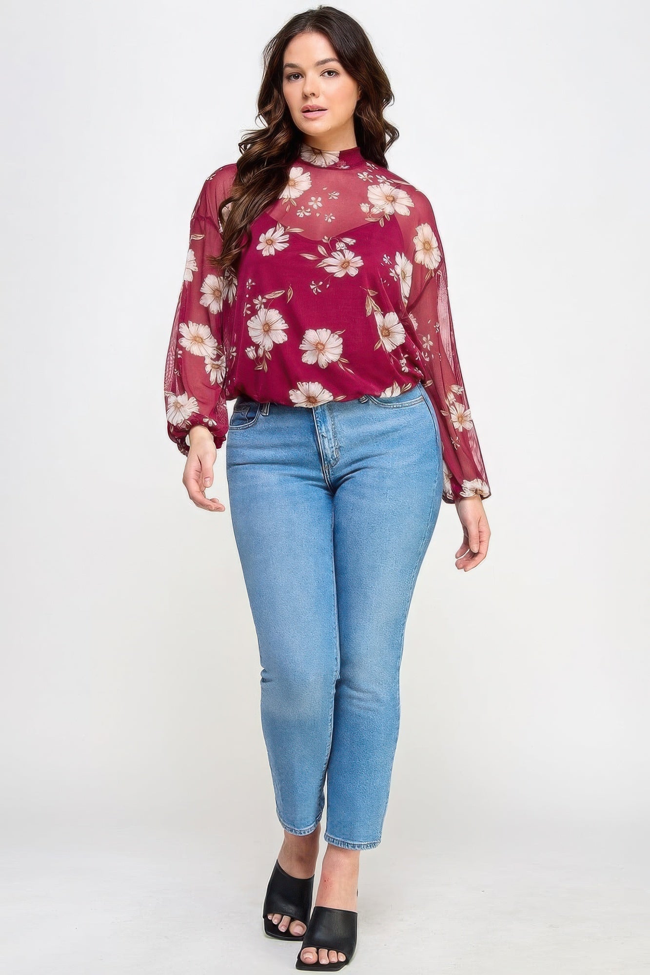 Woman wearing a mesh floral long sleeve top with cami from Loveitclothing.com, paired with blue jeans and black heels.