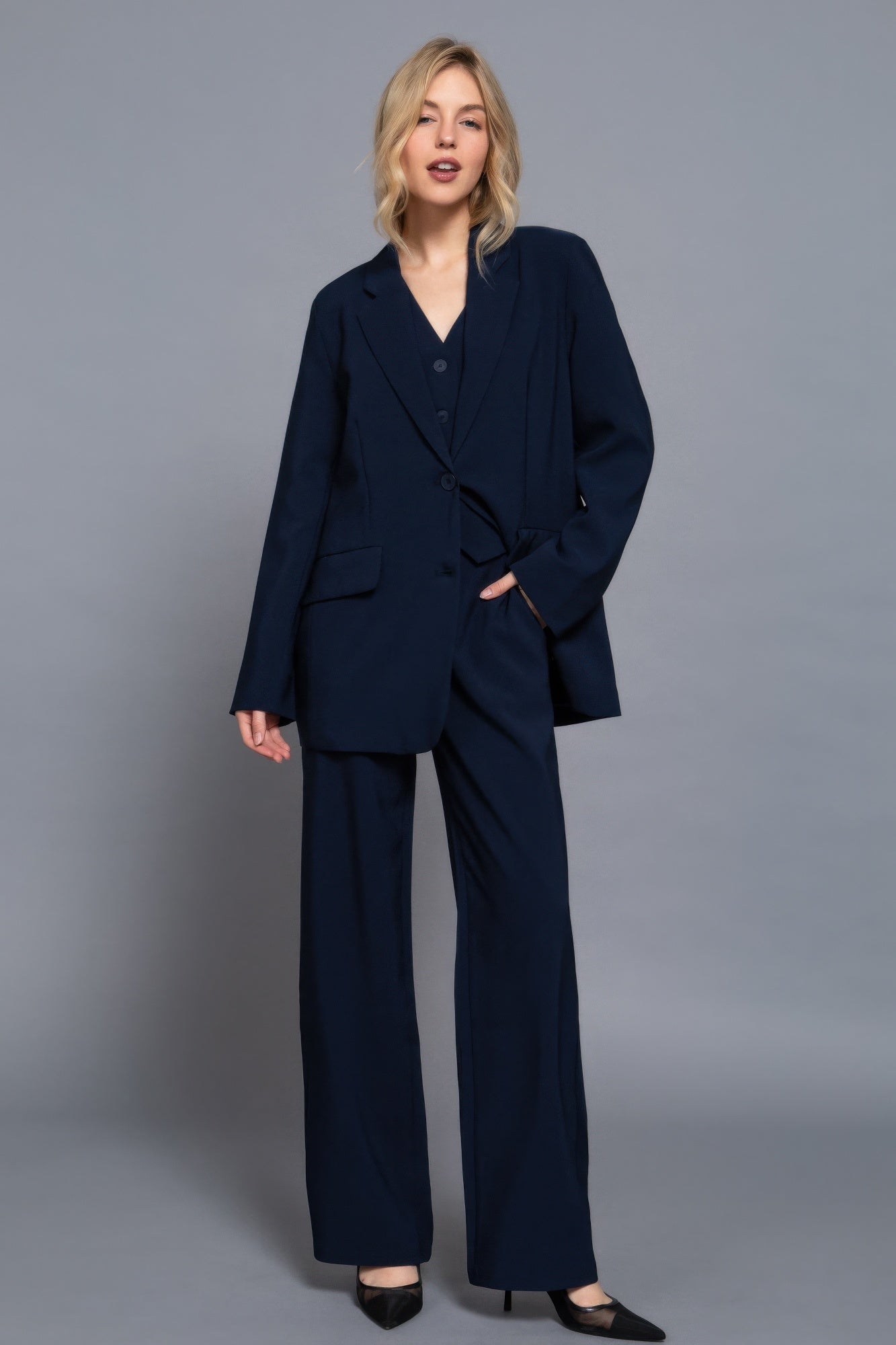 Model wearing navy back elastic straight-woven long pants and matching blazer on gray background.