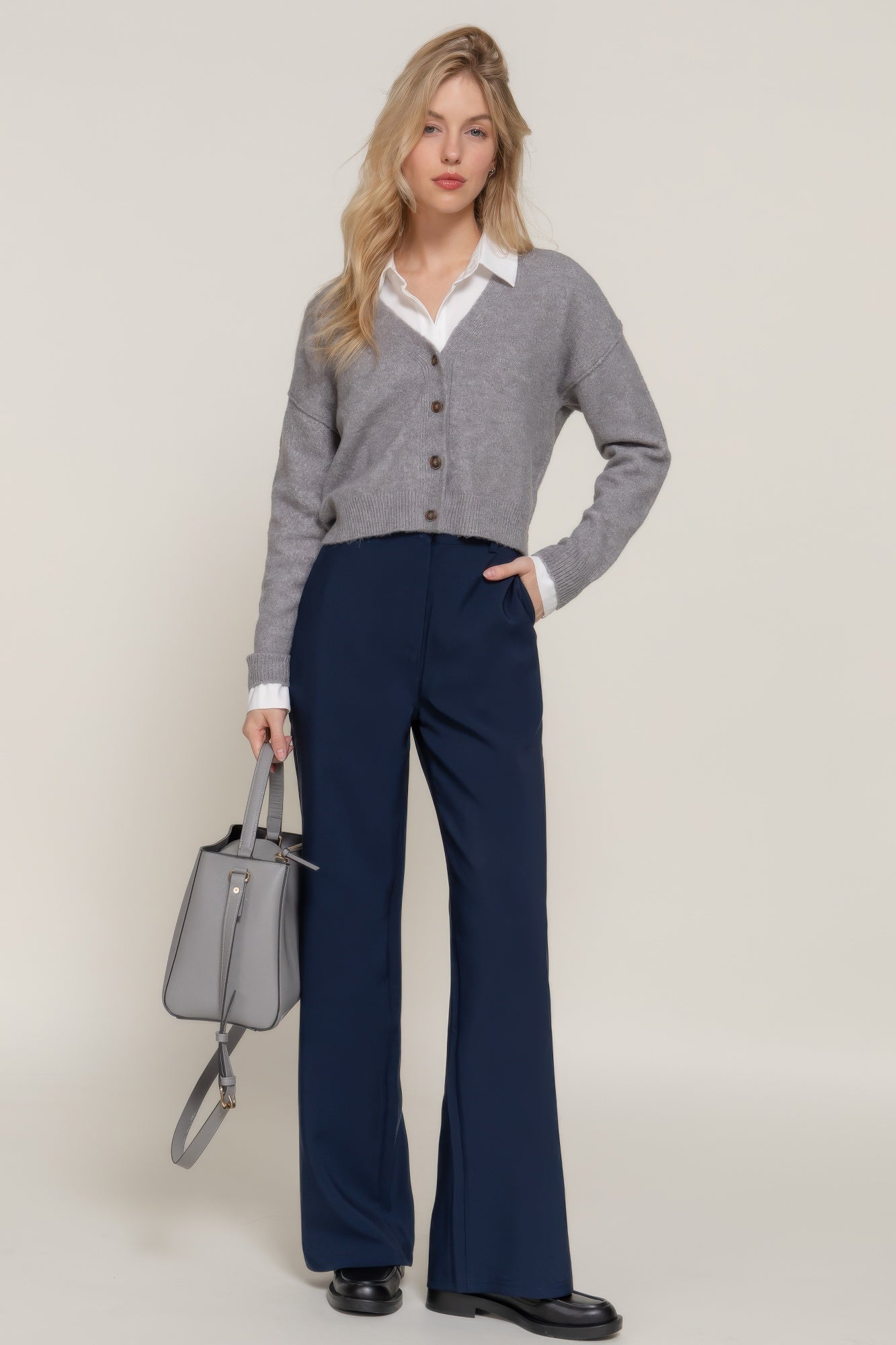 Model wearing back elastic straight woven long pants in navy, styled with a gray cardigan and holding a handbag.