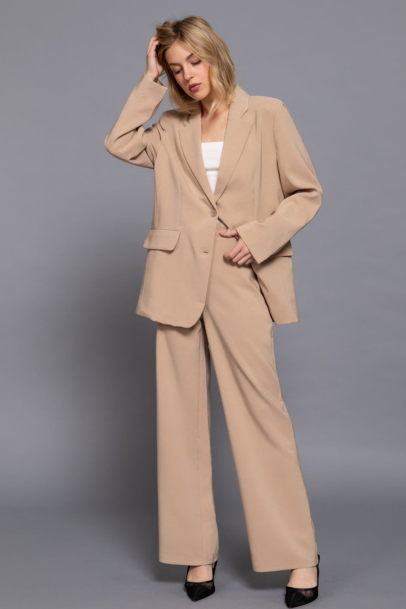 Stylish woman in beige oversized blazer and wide-leg pants, showcasing modern business attire.